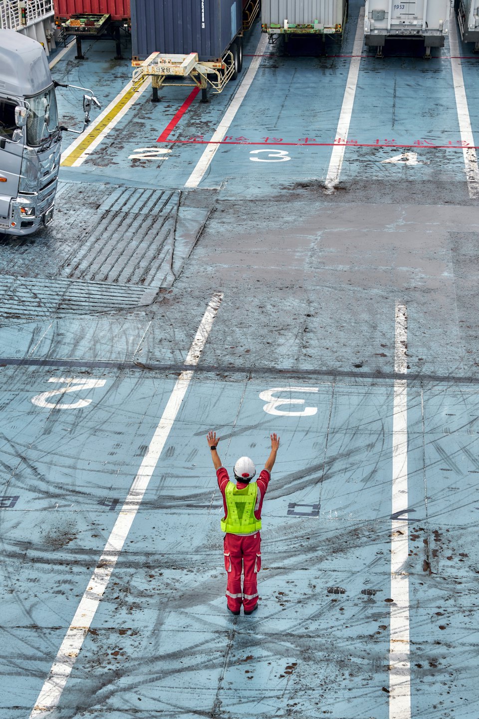 Arbetare i skyddsutrustning dirigerar trafik på industriplattform.